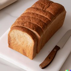 a loaf of bread sitting on top of a white cutting board next to a knife