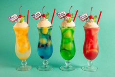 four different types of drinks in glasses with straws and labels on them, lined up against a blue background