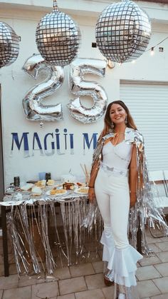 a woman standing in front of a table with silver balloons