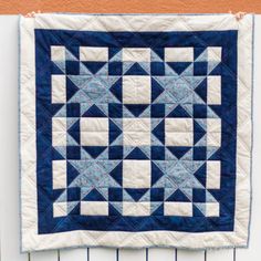 a blue and white quilt hanging on a wall