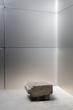 a stone bench sitting in the middle of a room with white walls and flooring