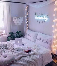 a bed with white sheets and lights around it