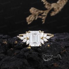 an emerald and white topazte ring on rocks with flowers in the back ground