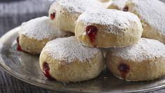 powdered sugar covered pastries are on a silver platter with jam in the middle