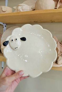 a hand holding a white bowl with a sheep face on the front and black nose