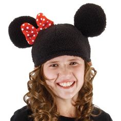 a girl wearing a minnie mouse hat with a red polka dot bow on her head