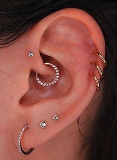 a woman wearing three different types of ear piercings