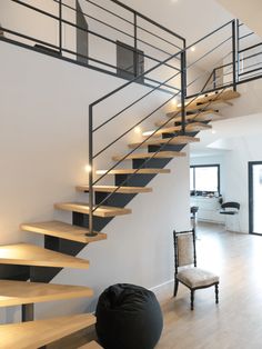 there is a black bean bag sitting on the floor next to some stairs and a chair