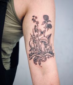 a woman with a tattoo on her arm has flowers and plants in the water behind her