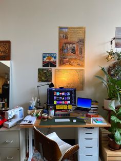 a desk with a laptop and computer on top of it next to a potted plant