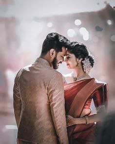 a man and woman standing next to each other in front of a building with lights