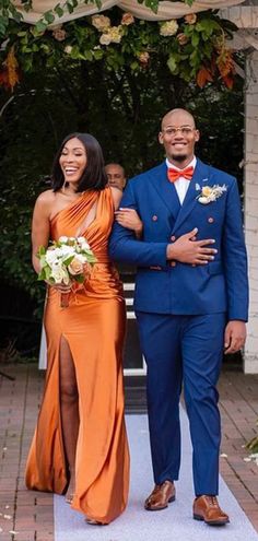 a man and woman in formal wear walking down the aisle at an outdoor wedding ceremony