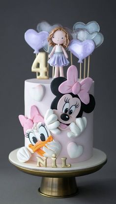 a birthday cake decorated with mickey mouse and minnie mouse figurines on a stand