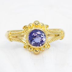 Unleash your inner classic beauty with this Tanzanite Classical Ring, a luxurious 18K gold piece featuring intricate Etruscan granulation and a lovely 6mm tanzanite. Enjoy wearing this gorgeous ring for any occasion. 18K granulated gold featuring a row of granulation down each side as well as on the sides of the bezel. This elegant ring is set with a 6mm tanzanite and a beveled lower band. Shown in a size 8, but each ring comes with free sizing and FREE SHIPPING! Unsure what ring size you are? I Low Band, Gold Piece, Elegant Ring, Classic Beauty, Sapphire Ring, 18k Gold, Sapphire, Ring Size, Band