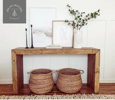 two baskets sitting on top of a wooden table next to a vase with flowers in it