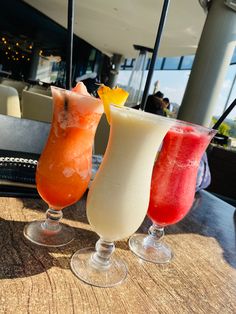 three different colored drinks sitting on top of a table