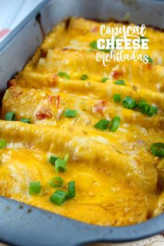 cheesy enchiladas in a blue casserole dish with green onions