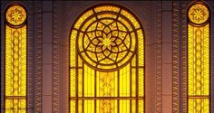 an ornate stained glass window in the front of a building with yellow light coming through it