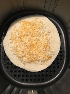 an uncooked pizza sitting on top of a black grill grate with cheese sprinkled all over it