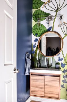 a bathroom with blue walls and green leaves painted on the wall above the vanity area