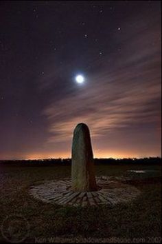 a large rock in the middle of a field at night