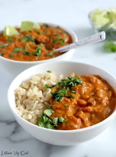 two bowls filled with rice, beans and cilantro on top of a table