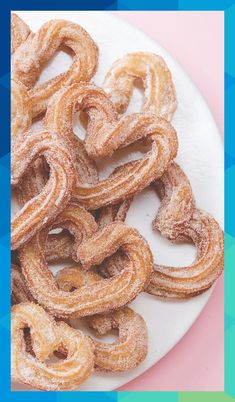 powdered sugar coated pretzels on a white plate against a pink background,