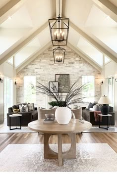 a living room filled with furniture and a chandelier hanging from the vaulted ceiling