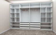 an empty room with white shelves and drawers