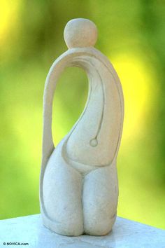 a white statue sitting on top of a table next to a green tree in the background