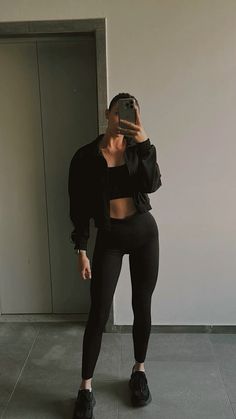 a woman taking a selfie with her cell phone while wearing black leggings