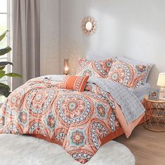 an orange and grey bed in a bedroom with white furnishing on the floor