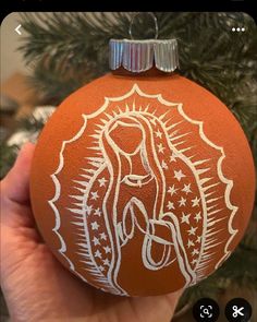 a hand holding an ornament with the image of mary on it