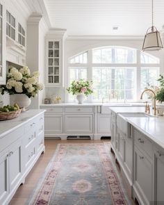 a large kitchen with white cabinets and an area rug on the floor in front of it