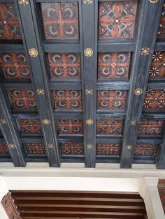 the ceiling is decorated with intricate designs and wooden slatted doors, which are painted black