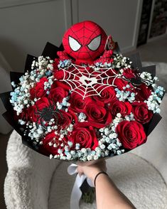 someone holding a bouquet of red roses with a spiderman on it