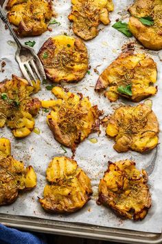 baked potatoes with herbs and seasoning on a baking sheet, ready to be eaten