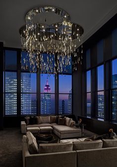 a living room filled with lots of furniture and a chandelier hanging from the ceiling