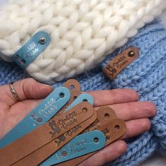 someone is holding some small leather tags in their hand and they are all knitted together