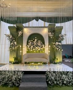 a stage set up for a wedding ceremony with flowers and greenery on the side