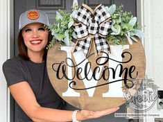 a woman holding up a welcome sign in front of a door