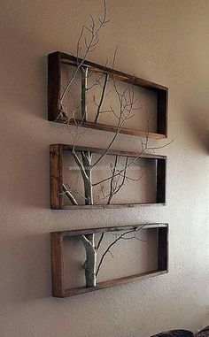 two wooden boxes with branches in them are hanging on the wall next to a bed