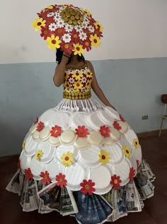 a woman in a dress made out of paper plates and flowers is holding an umbrella over her head