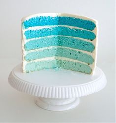 a blue and white cake sitting on top of a white cake plate with a slice taken out of it