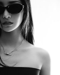 a woman wearing sunglasses is posing for a black and white photo with her hair blowing in the wind