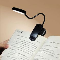 a person is holding an open book with a light on it and reading a book