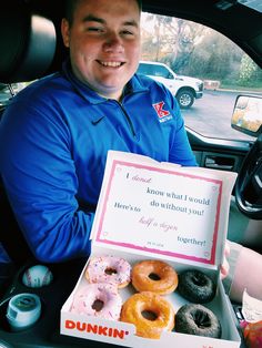 a man sitting in the back seat of a car holding a box of doughnuts