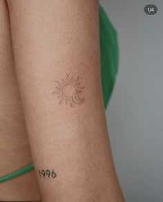 a woman's arm with a small sun tattoo on the left side of her arm