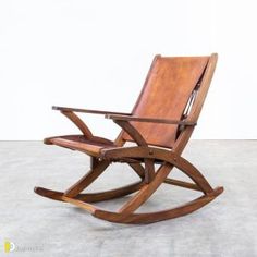 a wooden rocking chair sitting on top of a cement floor next to a white wall