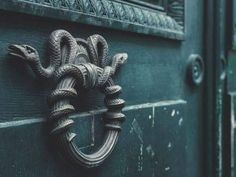 a close up of a door handle on a green door with an ornate knot around it